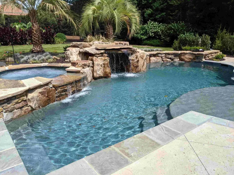 Custom gunite pool in Powdersville, SC with a rock waterfall spilling into it beside a raised spa